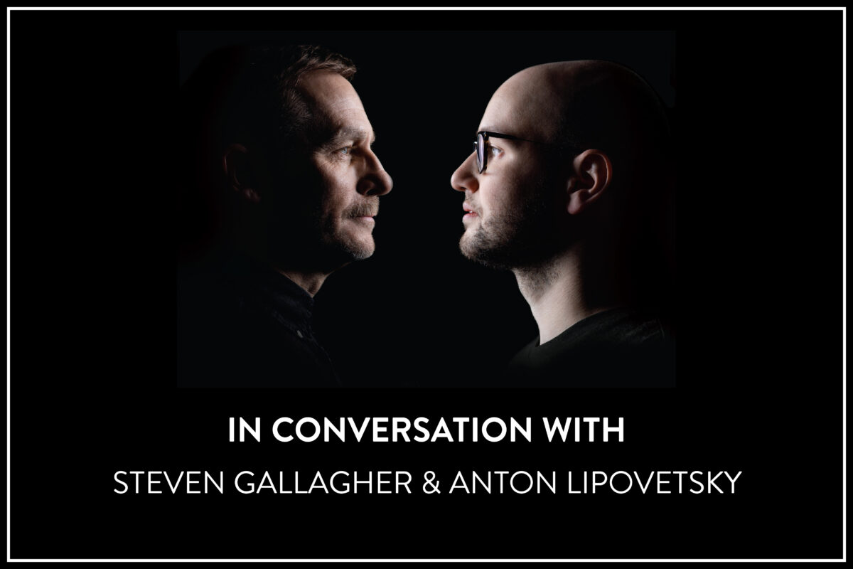 The top half of the frame features dramatic profiles of two white men facing each other in shadow against a black background. The left (Steven Gallagher) has dark features and a moustache, the right is bald and wearing black rimmed glasses (Anton Lipovetsky). Centered below the image, in all-caps reads, "In conversation with Steven Gallagher & Anton Lipovetsky"