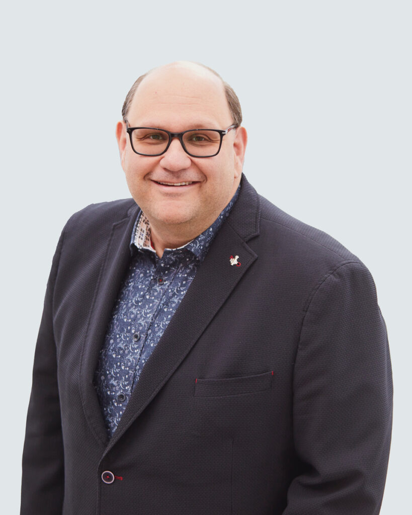 Headshot image of Michael Rubinoff. Michael is wearing black framed glasses, a black suit jacket, and a blue patterned collared shirt.