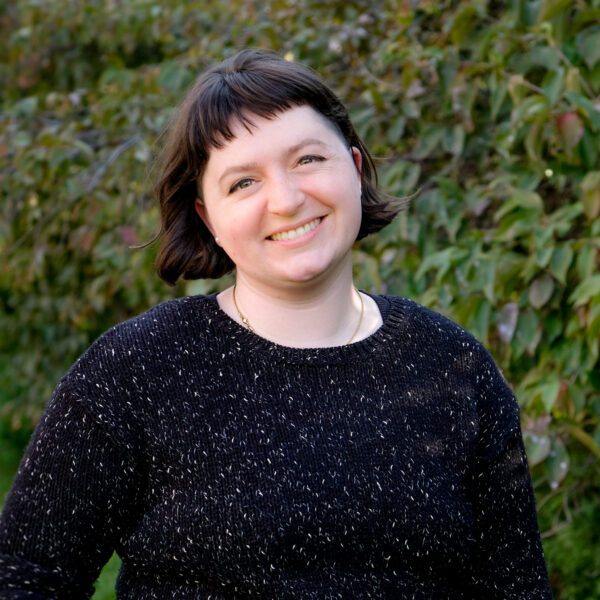 Photo of Lucy. Lucy is smiling, has short hair and is wearing a pullover sweater.